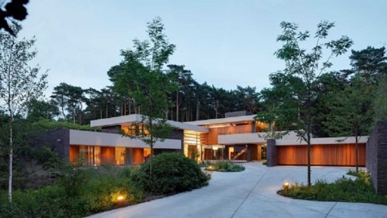 Home exterior with large swaths of natural wood which softly lit at night