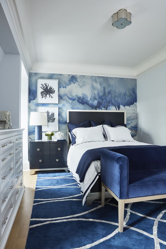 A-bold-bedroom-with-a-watercolor-blue-accent-wall-and-navy-furniture-and-a-rug-for-a-sea-inspired-feel