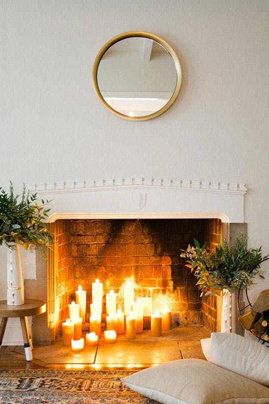 A-hygge-fireplace-with-lots-of-candles-and-greenery-arrangements-in-beautiful-vases-for-a-natural-feel