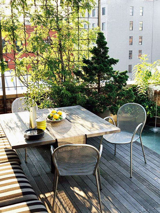A-small-and-cozy-terrace-with-an-upholstered-bench-a-wooden-table-metal-chairs-and-a-mini-garden-in-pots