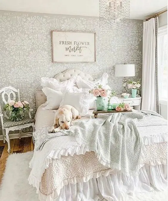A-pastel-vintage-bedroom-with-a-printed-wallpaper-wall-a-refined-bed-and-nightstands-printed-bedding-and-a-crystal-chandelier