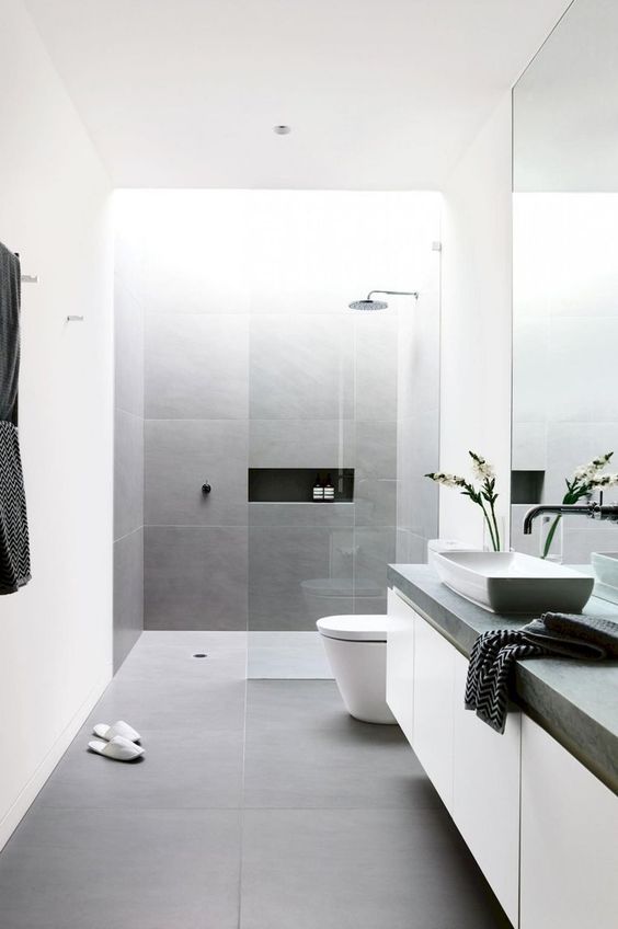 A-minimalist-bathroom-clad-with-grey-and-white-tiles-a-floating-vanity-a-concrete-countertop-and-a-large-mirror